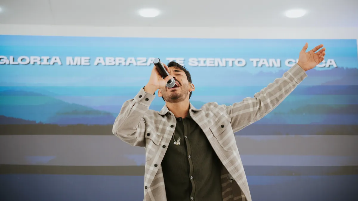 Líder de alabanza adorando con los brazos abiertos en Somos Iglesia