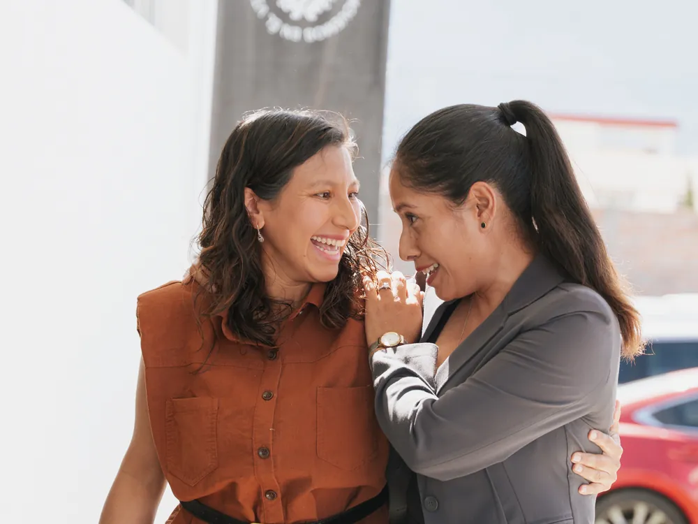 Dos amigas de un GPS abrazadas y sonriendo