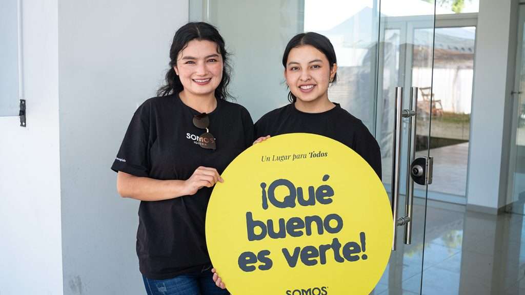 Anfitriones recibiendo a las personas con un cartel de ¡Qué bueno es verte!